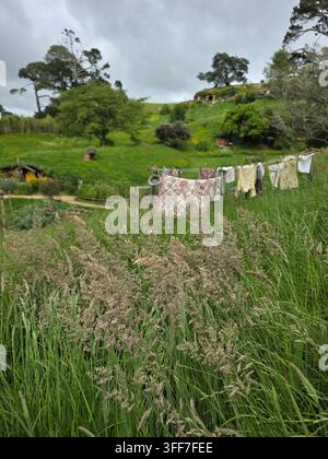 Ikoniisches Hobbit-Haus mit einer gelben runden Tür, Grasdach und winziger Wäsche, die an einer Wäscheleine im Garten hängt, Hobbiton, Matamata, Neuseeland Stockfoto