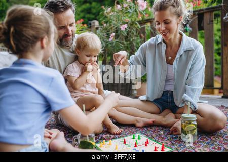 Familie genießt ein Brettspiel zusammen auf der Außenterrasse im Sommer. Stockfoto
