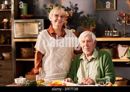Porträt eines glücklichen Seniorenpaares, das in der Küche eine gesunde Mahlzeit zubereitet Stockfoto