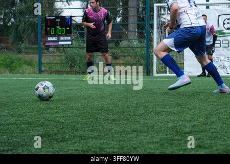 Kiew Ukraine 05. September 2026 Ein klassischer Futsalball rollt auf einem Kunstrasenplatz, während Fußballspieler und eine elektronische Anzeigetafel sichtbar sind Stockfoto