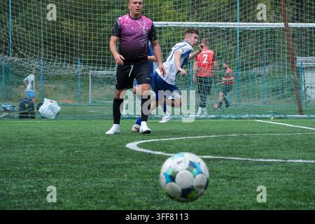 Kiew Ukraine 05. September 2026 Ein Futsalball liegt im Vordergrund, während Fußballspieler auf einem künstlichen grünen Rasenfeld während eines intensiven Mi... Stockfoto