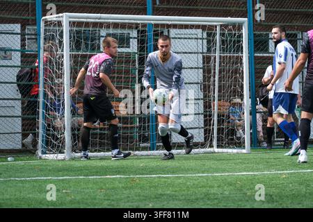 Kiew, Ukraine – 05. September 2026 Ein Torwart in grauer Uniform fängt einen Fußball während eines Outdoor-Mini-Fußball-Turniers. Stockfoto