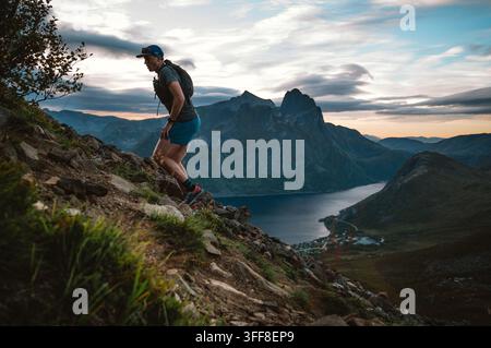 Mann läuft bei Sonnenaufgang einen steilen Berg hinauf Stockfoto