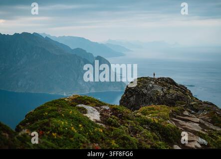 Wanderer steht auf dem Berggipfel mit Blick auf den Ozean Stockfoto