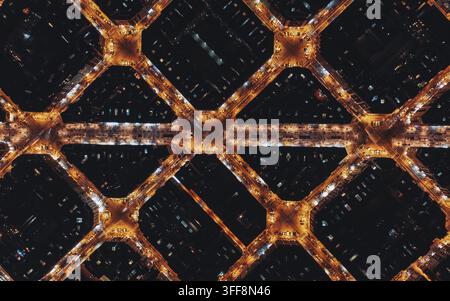 Luftaufnahme des Eixample-Viertels bei Nacht, das das ikonische Rastermuster von achteckigen Stadtblöcken zeigt, die von Straßenlaternen beleuchtet werden, Barcelona, Katalonien Stockfoto