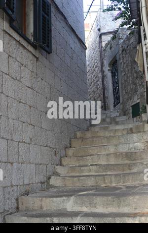 Traditionelle dalmatinische Stein-Gasse mit Treppen, Mauerwänden und dunklen Holzläden, Altstadt von Cavtat Stockfoto