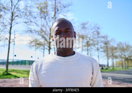 Reifer Mann lächelt im Freien in einem städtischen Park. Stockfoto