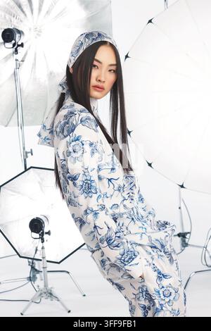 Vertikales Studio-Modenporträt eines jungen asiatischen Models in einem blau-weiß botanischen Blumenmuster-Anzug. Stockfoto