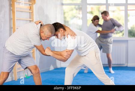 Typ und älterer Sportler führen ein Trainingsduell in orientalischer Kampfkunsttechnik durch. Schule für Kampfkunst. Stärkung der Geisteskraft an Stockfoto