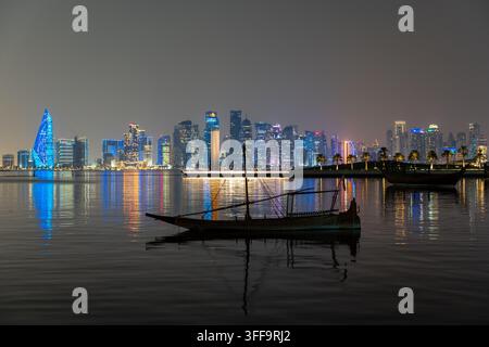Doha, Katar - 11. November 2025: Weite Aufnahme der Skyline des Finanzdistrikts West Bay von Doha und der monumentalen 7-Skulptur im MIA-Park bei Beleuchtung. Stockfoto