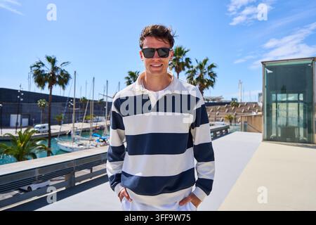 Junger Mann mit Sonnenbrille in der Yachthafenanlage Stockfoto