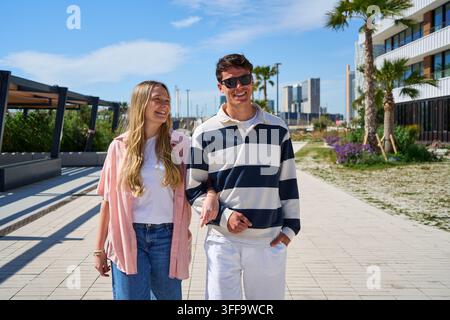 Glückliches junges Paar geht zusammen auf der Stadtpromenade spazieren Stockfoto