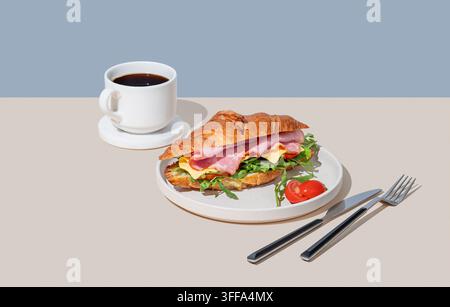 Croissant-Sandwich mit Schinken, Käse, Tomate und Rucola auf einem Teller vor einem hellen Hintergrund mit einer Tasse frisch gebrühtem Kaffee. Konzept für ein gesundes Frühstück Stockfoto