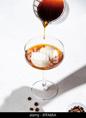 Affogato-Kaffee mit Vanilleeis-Schnitten und ergossenem Espresso auf weißem Hintergrund mit Kaffeebohnen und Schatten. Klassisches italienisches Dessertkonzept Stockfoto