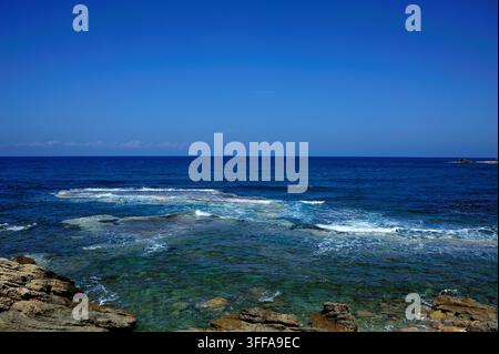 Ruhige malerische Aussicht auf türkisfarbene Wellen des Mittelmeers, die sanft über Küstenfelsen und Riffe in Caesarea, Israel, brechen Stockfoto