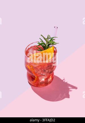 Roter orangefarbener Cocktail oder Limonade mit Eis und Rosmarin auf einem rosa Hintergrund mit Schatten. Sommerliches Zitrusgetränk-Konzept für ein Café-Menü-Werbebanner. Stockfoto