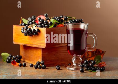 Glas Aroniabeer und frische Beeren in einer Holzkiste. Stockfoto