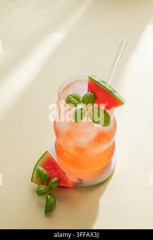 Wassermelonen-Mojito-Cocktail mit Eis und Minze in einem Glas auf gelbem Hintergrund mit Schatten. Sommerliches erfrischendes Limonaden-Getränkekonzept für Werbung b Stockfoto
