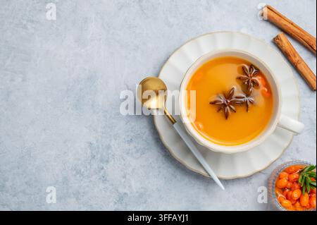 Sanddorn-Kräutertee in einer Tasse auf hellem Hintergrund mit Gewürzen, Beeren und Löffel. Konzept für ein heißes, organisches Herbstgetränk zur Stärkung der Immunabwehr. Oben Stockfoto