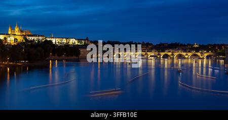 Boote bewegen sich auf dem Fluss, während Lichter sich auf dem Wasser in Prag nach Sonnenuntergang spiegeln. Stockfoto