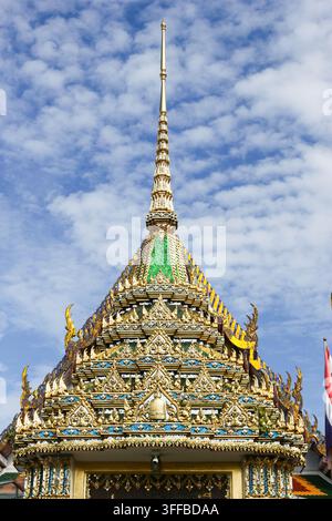 Verschnörkelter goldener Turm und gestuftes Dach des Tempeltors von Wat Rakhang Khositaram, Bangkok, Thailand, aus einem niedrigen Winkel gesehen. Stockfoto