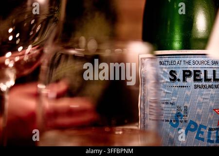 23. Nov 2011 - LondonUK - Pellegrino-Wasser auf dem Tisch mit verschwommenen Weingläsern im Hintergrund Stockfoto