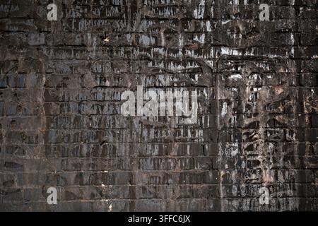Angebrannte Ziegelwand mit schwarzer Rußtextur im Hintergrund. Stockfoto