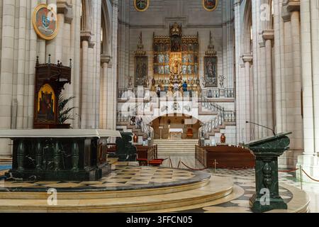 Madrid, Spanien: 7. Apr. 2025 - Das lange Marmorbasilika der Almudena-Kathedrale führt zu einem kunstvoll vergoldeten Altarbild und einem Buntglasfenster, mit ein paar Visis Stockfoto