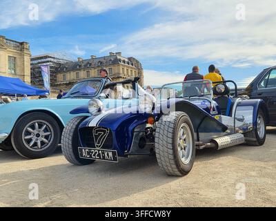 Vorderdreiviertelansicht eines dunkelblauen klassischen Sportwagens und eines hellblauen Oldtimers, die im Freien während einer Aut Ausstellung unter einem blauen Himmel geparkt sind. Stockfoto