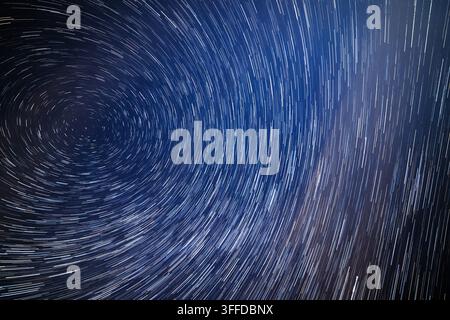 Langzeitbelichtung fängt die kreisförmige Bewegung der Sterne am Nachthimmel ein. Der Wirbeleffekt links steht im Kontrast zu den linearen Spuren rechts und zeigt die himmlische Schönheit. Stockfoto
