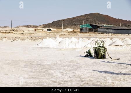 Salzhaufen, Bergbauwerkzeuge und ein Unterstand in der Danakil-Senke, Afar, Äthiopien, unter einer kargen vulkanischen Landschaft. Stockfoto