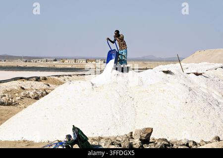 Salzarbeiter verwenden Schubkarren neben großen Salzanhäufungen in der Danakil-Senke, Afar, Äthiopien. Stockfoto