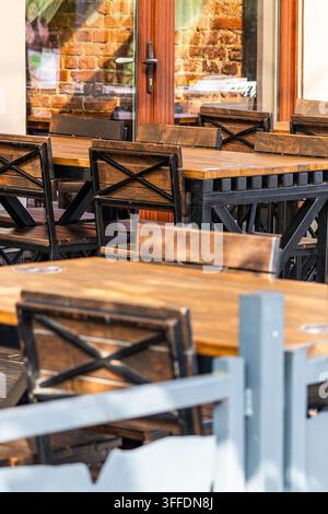 Außenrestaurant-Terrasse mit stabilen Holztischen und Stühlen mit Kreuzrücken-Metallrahmen. Stockfoto