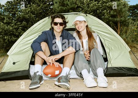 Porträt eines lächelnden Mannes und einer Frau, die in einem Campingzelt entspannen Stockfoto