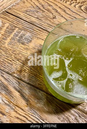Eisgetränk in grüner Farbe in klarem Glas auf rustikalem Holztisch. Stockfoto