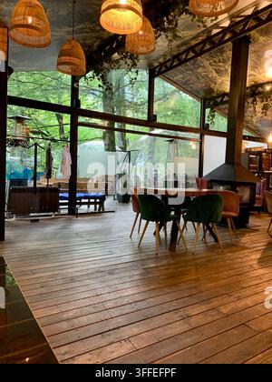 Ein leeres Waldrestaurant kombiniert Glaswände, Holzböden und warme Beleuchtung. Stockfoto