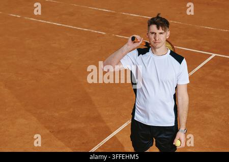 Porträt eines Mannes, der einen Tennisschläger auf einem Sandplatz hält Stockfoto