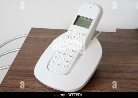 Modernes Festnetztelefon mit Digitaldisplay auf Holzoberfläche. Stockfoto