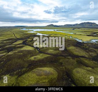Luftbild des Vulkans Maelifell, umgeben von lebendigem grünem, moosbedecktem Lavafeld und sich schlängelnden Wasserkanälen in Skaftarhreppur, Island. Stockfoto