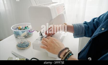 Frau arbeitet mit Nähmaschine an Stoff bei hellem Tageslicht Stockfoto