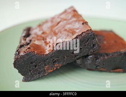 Nahaufnahme eines hausgemachten dunklen Schokoladen-Fudgy-Brownie-Stücks, das auf einem Teller serviert wird Stockfoto