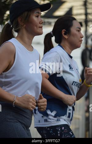 Seitenansicht von zwei aktiven asiatischen Frauen, die zusammen im Freien in der Stadt joggen Stockfoto