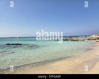 Kristallklares türkisfarbenes Wasser über einer flachen Lagune mit verstreuten Felsen am Strand von Elafonisi, Region Chania, südwestliche Küste von Kreta, Griechenland Stockfoto