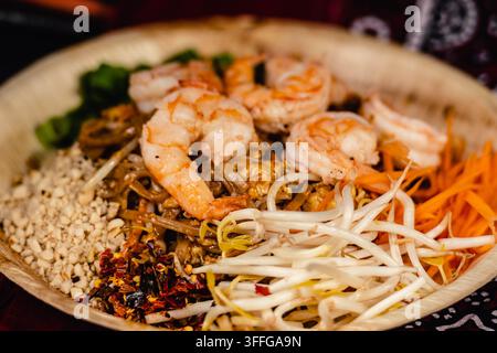 Pad-Thai-Gericht mit Garnelen, gebratenen Reisnudeln, Bohnensprossen, zerkleinerten Erdnüssen und Gemüse, serviert in einer Bambusschale Stockfoto