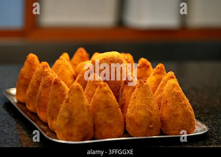 Knusprige italienische Arancini-Reiskugeln. Eine Nahaufnahme von frisch gebratenen, goldbraunen, kegelförmigen italienischen Arancini-Reiskugeln, die aufeinandergestapelt sind. Stockfoto