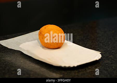 Knusprige italienische Arancini-Reiskugeln. Eine Nahaufnahme von frisch gebratenen, goldbraunen, kegelförmigen italienischen Arancini-Reiskugeln, die aufeinandergestapelt sind. Stockfoto