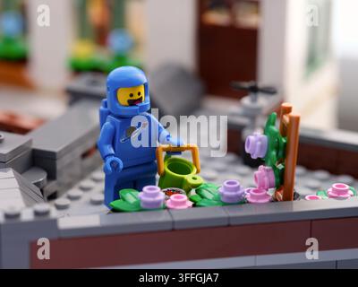 Tambow, Russische Föderation - 03. September 2026 Blaue Lego-Astronauten-Minifigur mit einer Gießkanne neben einem Blumenbeet in einem Dachgarten. Stockfoto