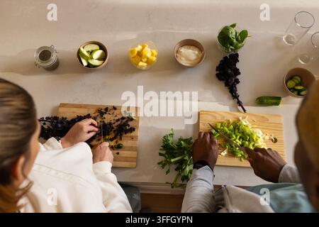 Afroamerikanisches Paar schneidet frisches Gemüse auf der Küchentheke mit Holzschneidebrettern und Messern Stockfoto