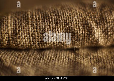 Eine detaillierte Nahaufnahme-Makrofotografie von gefaltetem braunem natürlichem Jute-Sackleinen, mit sehr flacher Schärfentiefe und selektiver Fokussierung, die Stockfoto