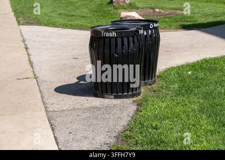 Schwarze Recyclingsammelbehälter in einem öffentlichen Park zur Sammlung verschiedener Abfallarten, die Recycling, Abfalltrennung und Umwelt repräsentieren Stockfoto